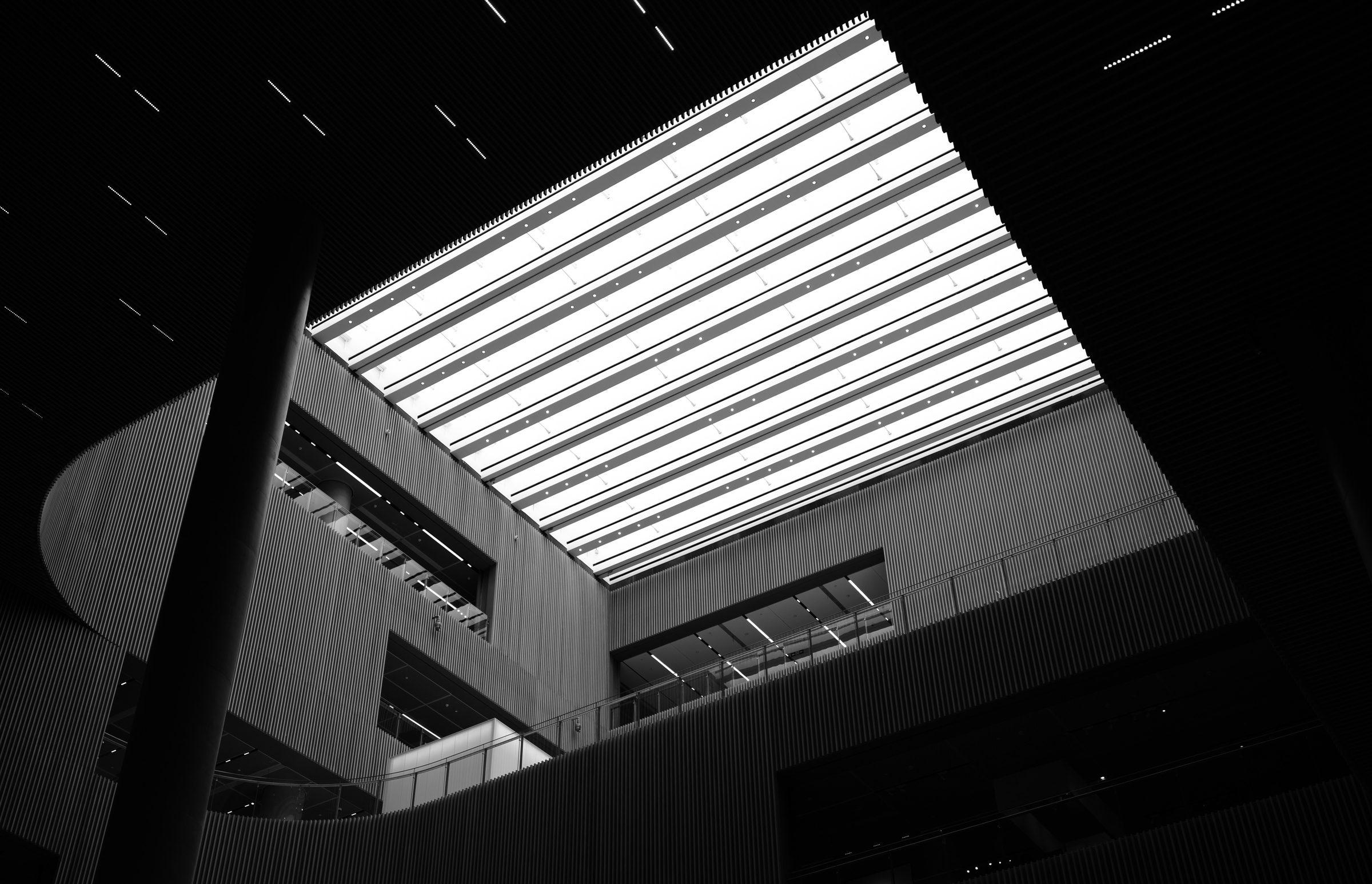 A dark building beneath a brightly louvred roof