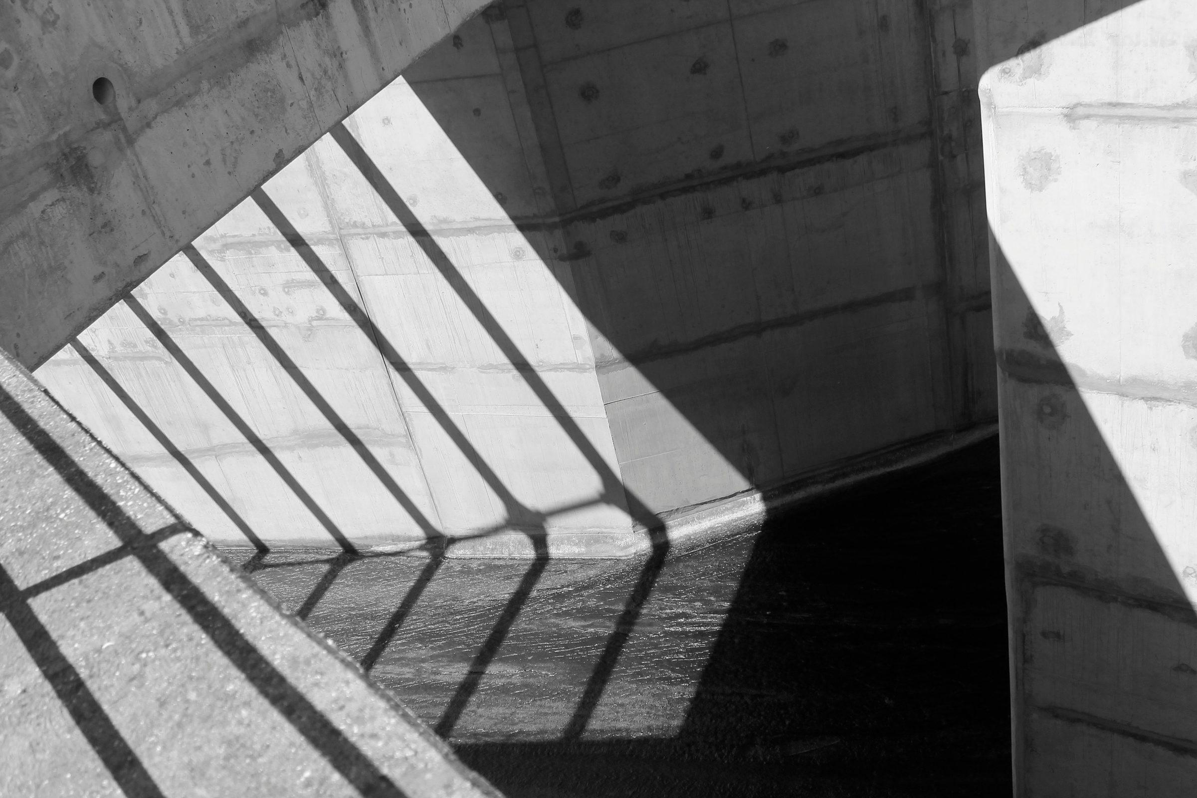 A concrete underpass barred with shadow